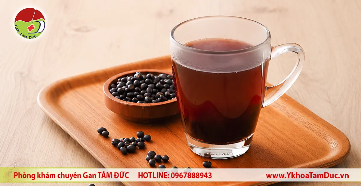 Uống Nước Đậu Đen Có Tốt Cho Gan Không? Góc Nhìn Y Khoa 1 Ly nước đậu đen và hạt đậu đen trên khay gỗ dùng minh họa bài viết về lợi ích của nước đậu đen đối với sức khỏe gan